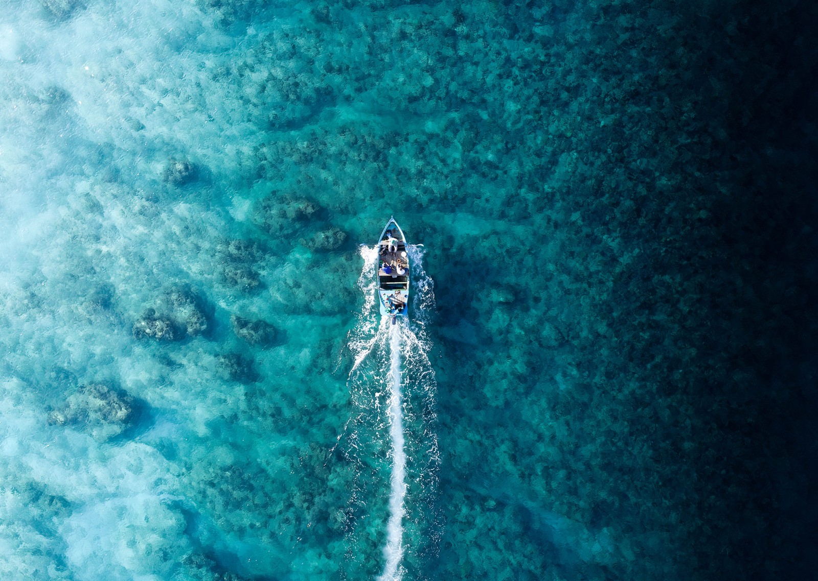 Aerial view of a boat sailing in the ocean with a jet ski (sea, ocean, beach, water, liquid)