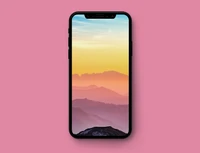 Smartphone Apple affichant un coucher de soleil sur des montagnes sur un fond rose