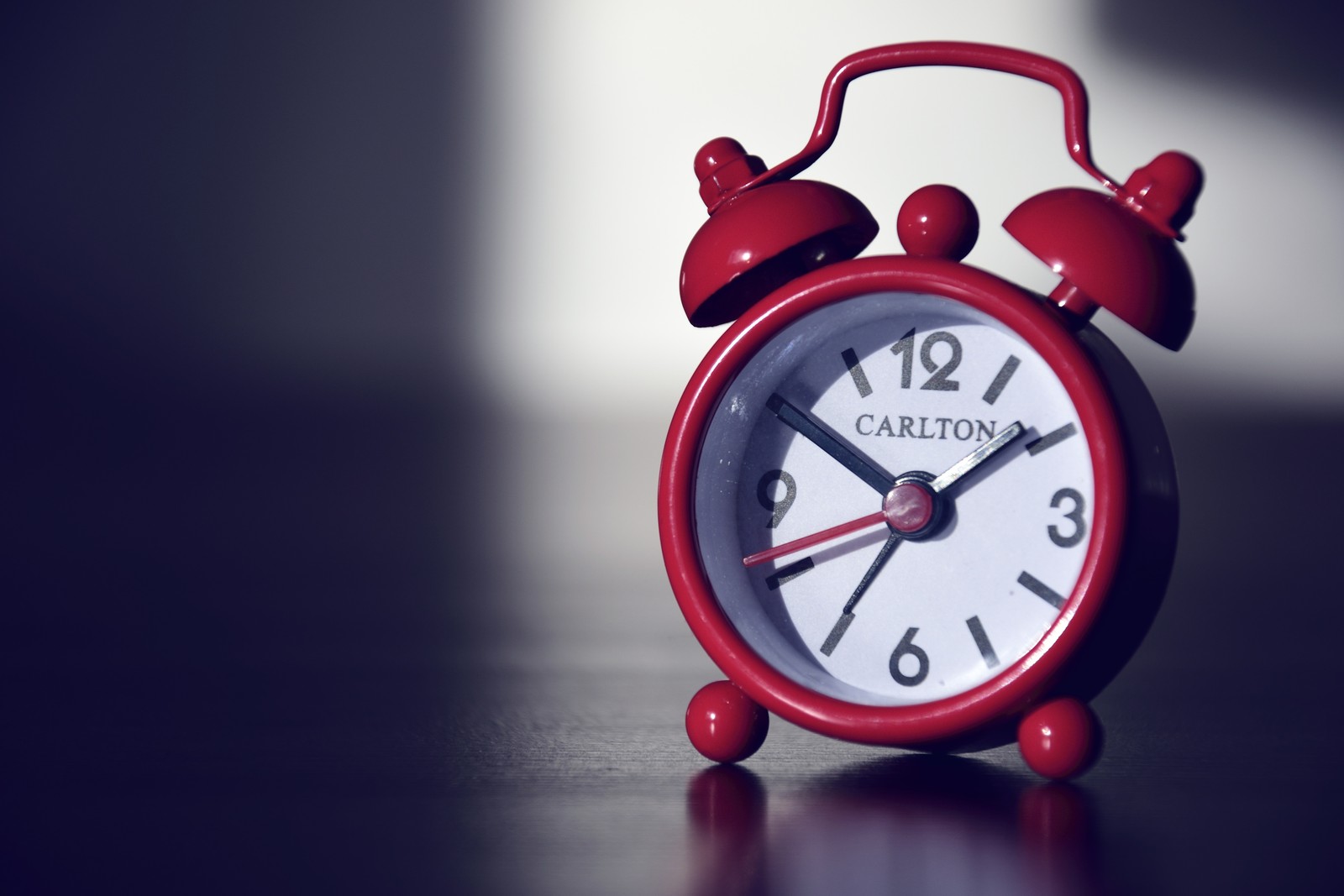 There is a red alarm clock sitting on a table with a white background (alarm clock, clock, red, interior design, still life)