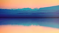 Serene Lake Landscape at Sunrise with Majestic Mountains in the Distance