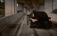 Porsche 911 GT2 noir sous un viaduc urbain