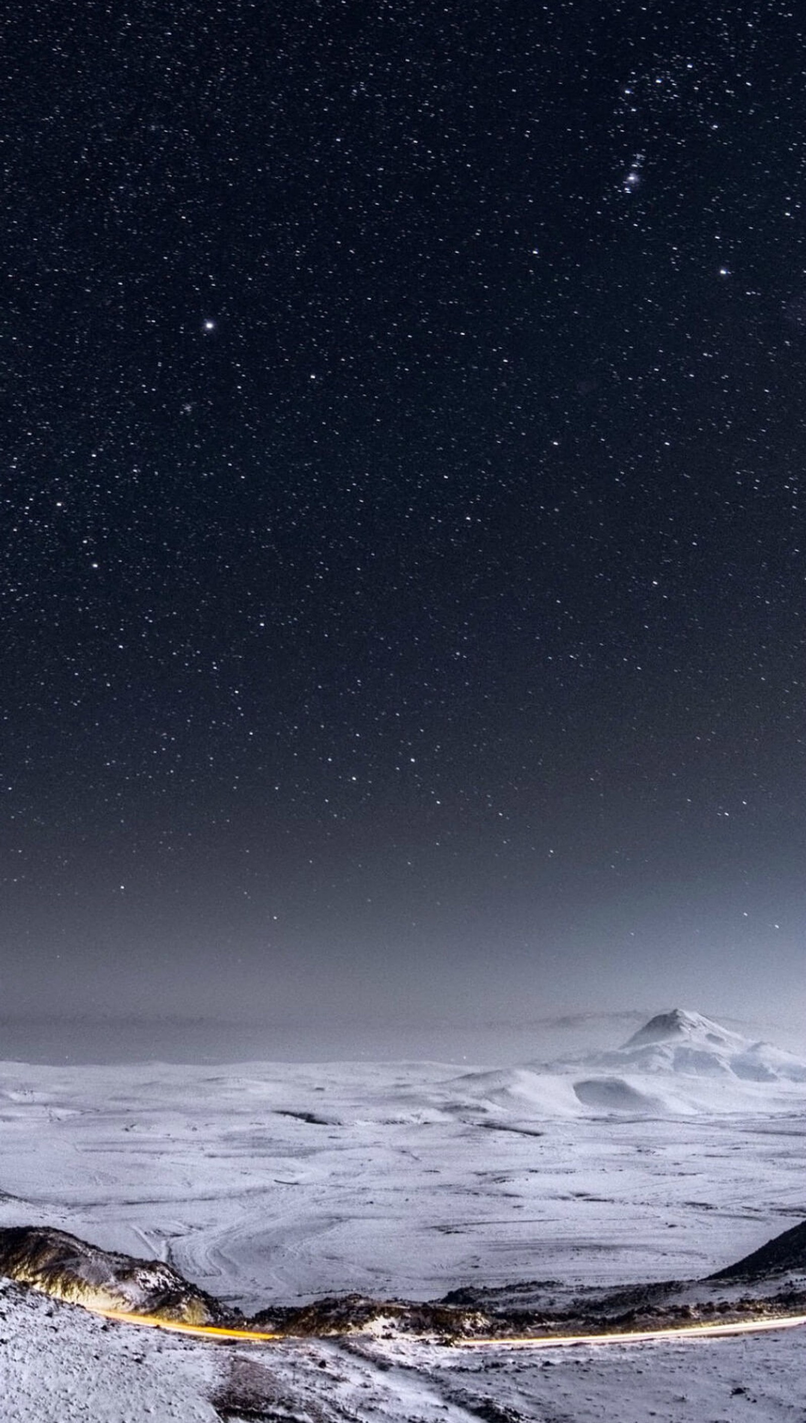 Starry night sky over a snowy mountain range with a road (sky, space)