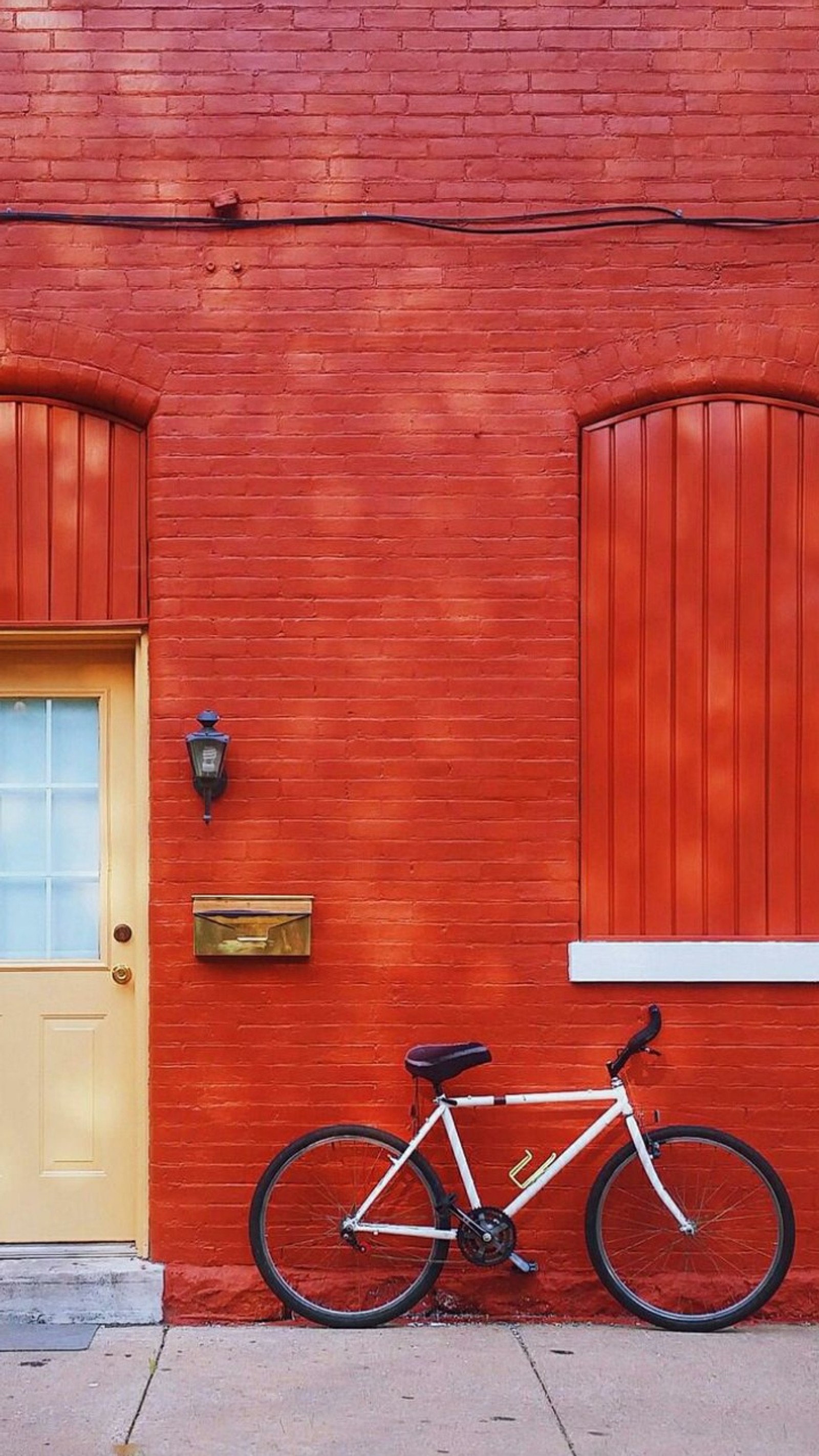 Il y a un vélo garé contre un mur en brique rouge à côté d'une porte jaune (beau, vélo, porte, maison, rouge)