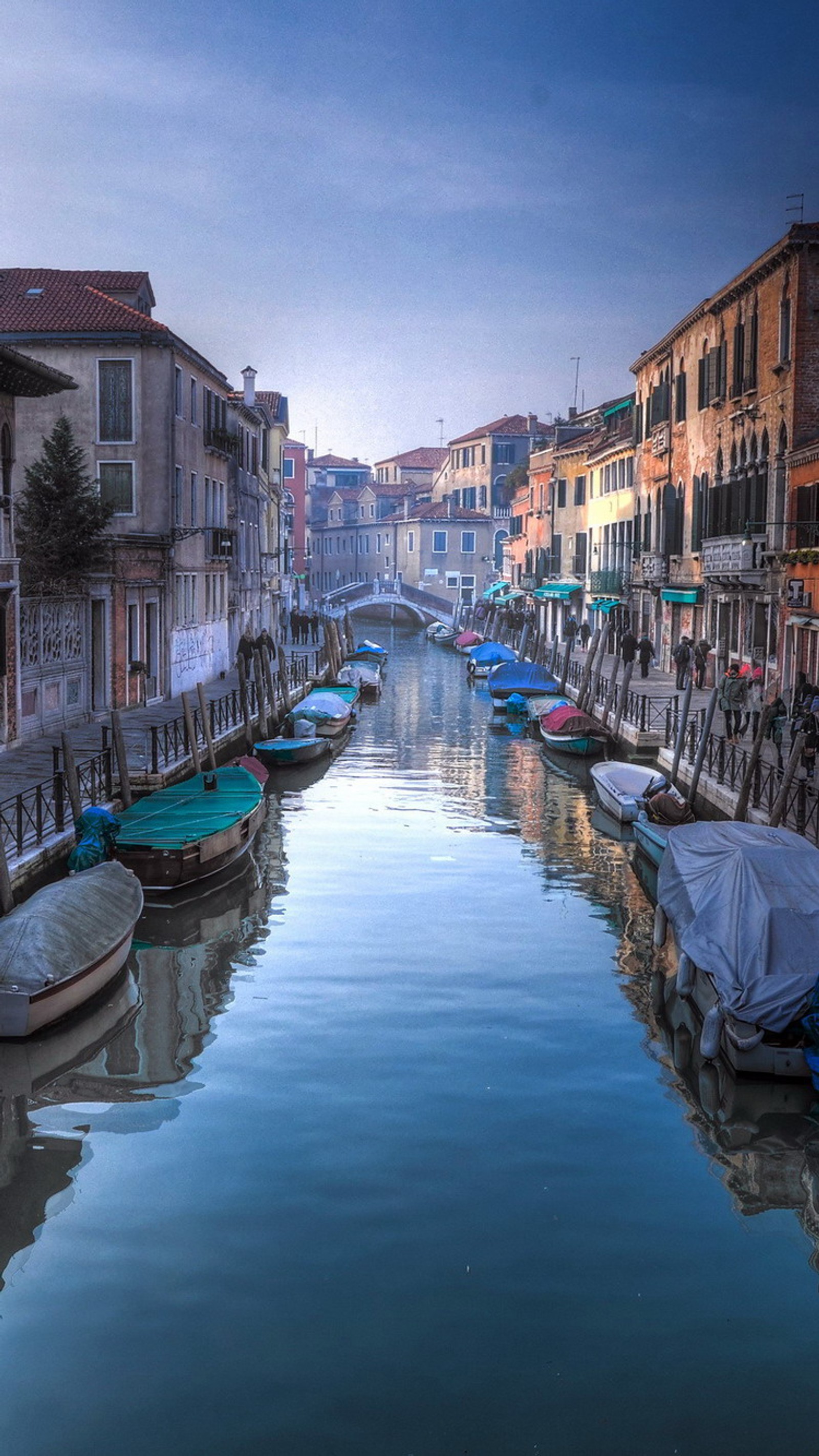 Barcos estão atracados ao lado de um canal em uma cidade (itália, venezzia)