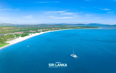 Vue aérienne de la plage de Pasikuda au Sri Lanka, mettant en valeur une côte vierge et des eaux bleues vibrantes.