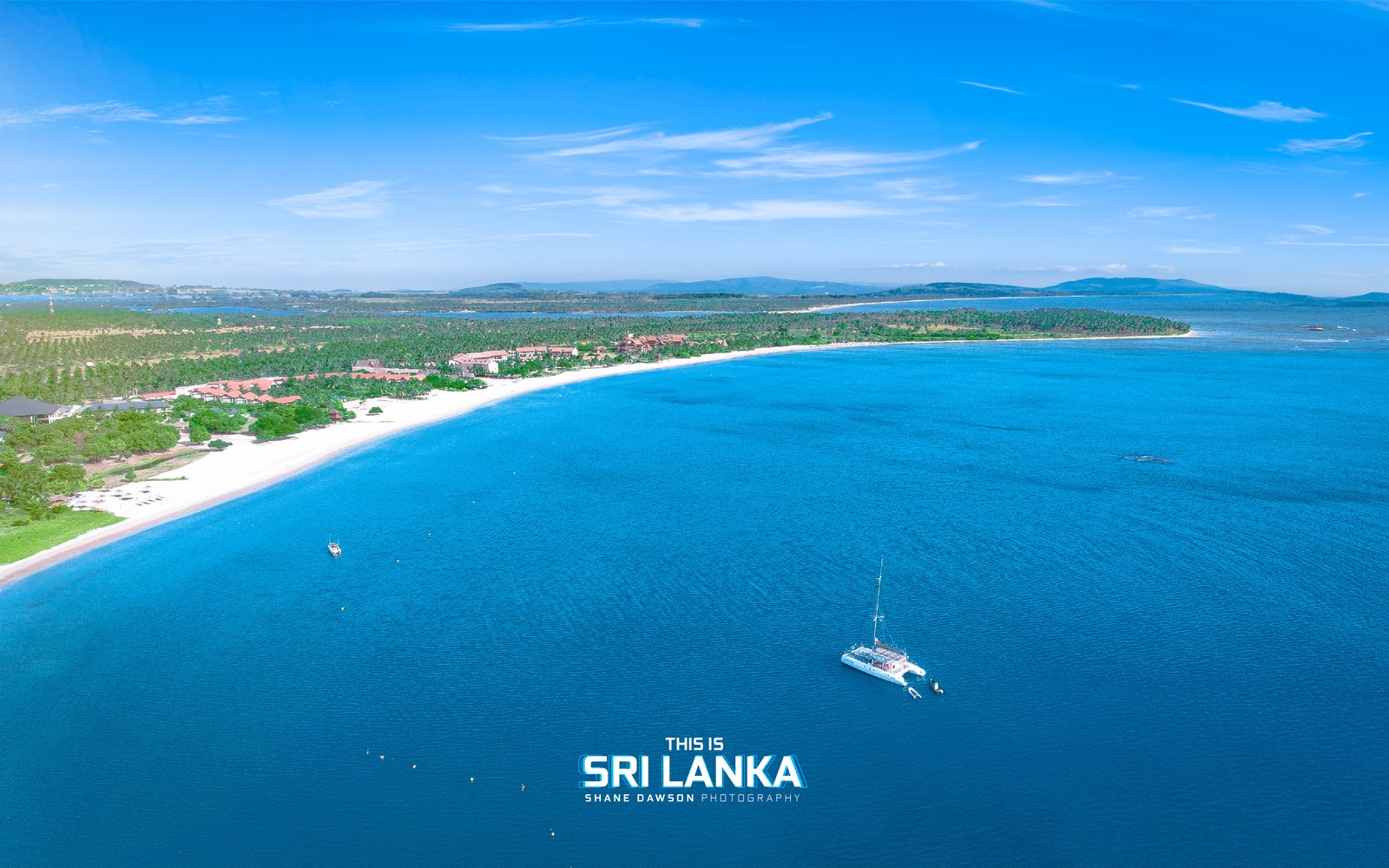 Uma vista de uma praia com um barco na água (pasikuda, sri lanka, travecloudlk)