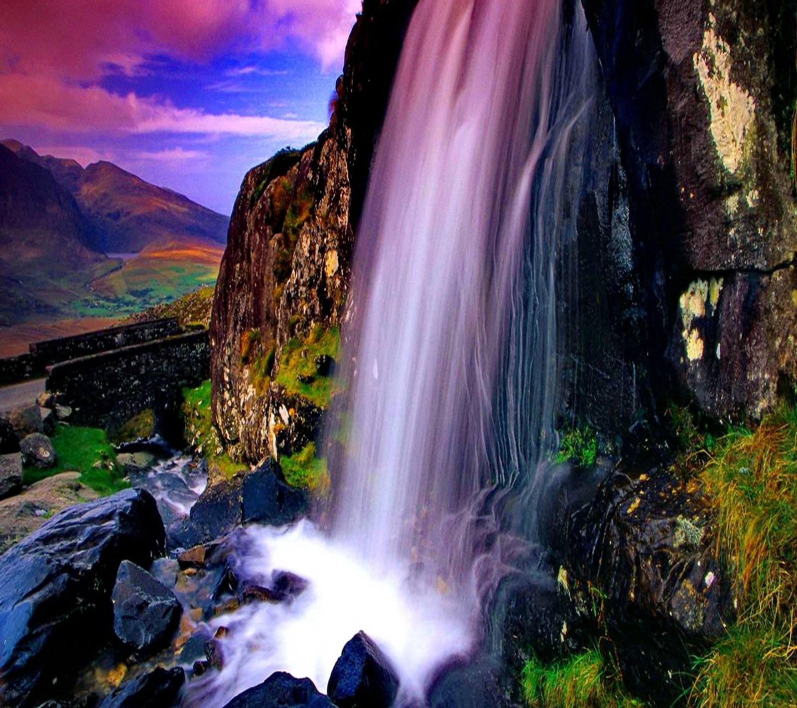 Cachoeira no meio de uma montanha rochosa com um céu rosa (verde, montanha, natureza, rosa, roxo)