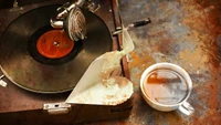 Fonógrafo vintage con disco y naturaleza muerta con taza de café