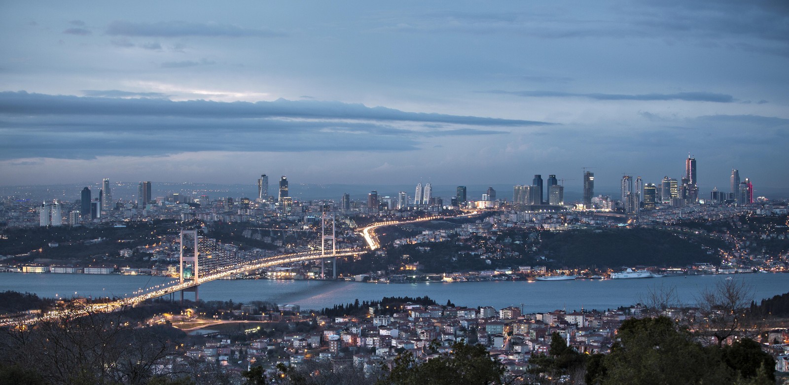 Hay una vista de una ciudad con un puente y un río en primer plano (nube, agua, rascacielos, recursos hídricos, atmósfera)