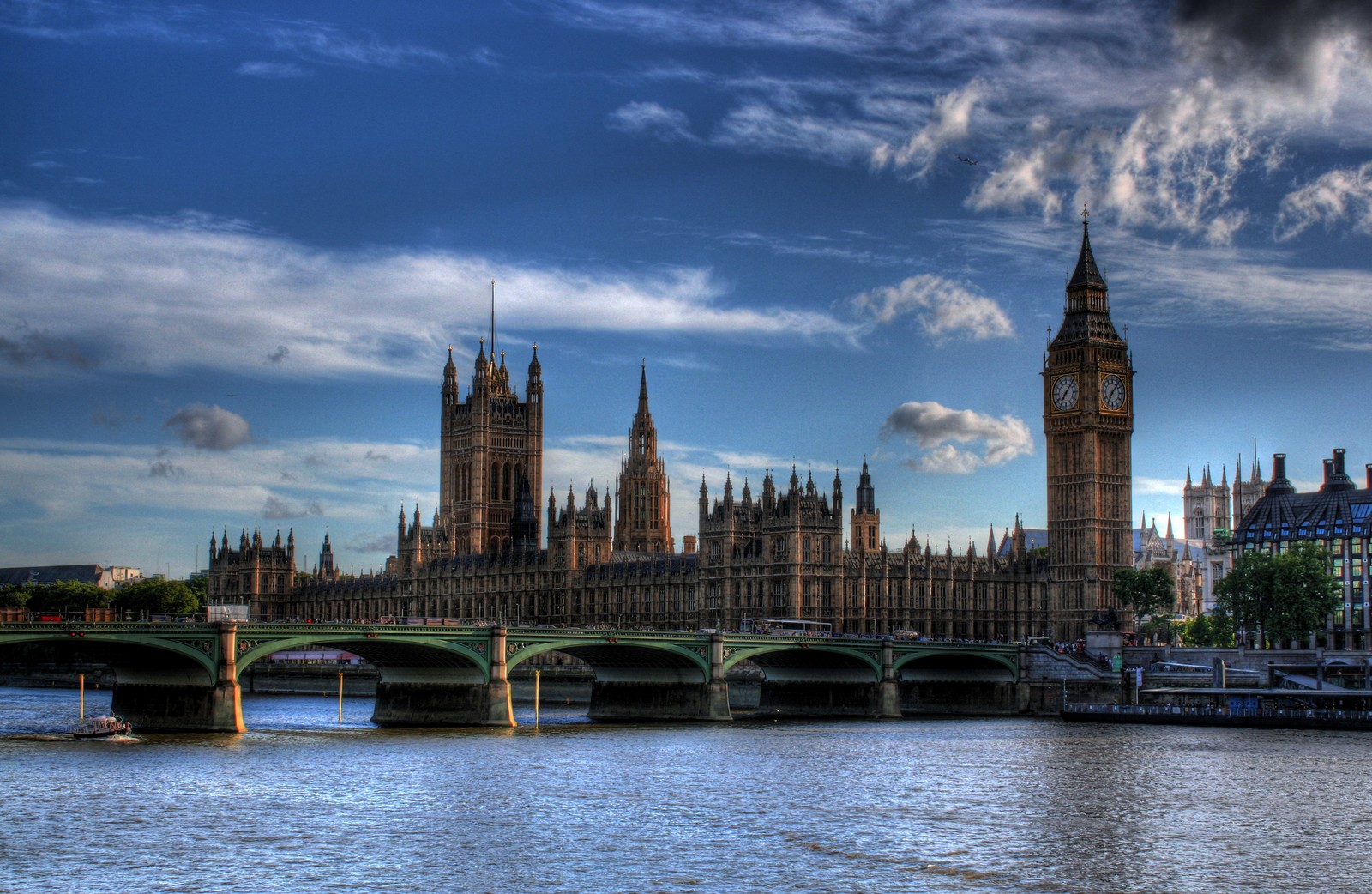 Una vista de un puente sobre un río con una torre del reloj al fondo (casas del parlamento, palacio de westminster, hito, rio, ciudad)