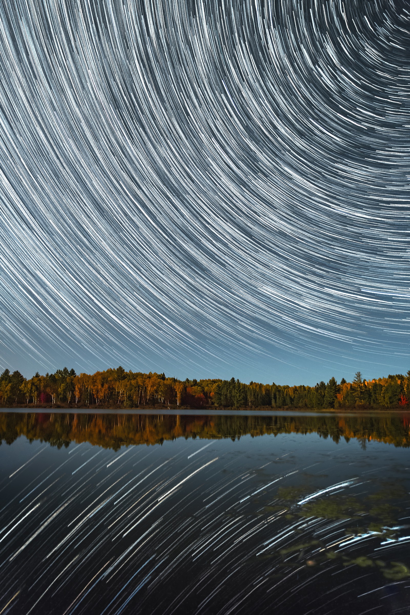 Arafed image of a lake with a star trail in the sky (tree, line, night, cloud, nature)