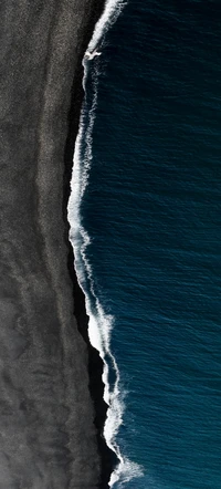 Ligne de rivage contrastante : sables sombres rencontrent des vagues bleu électrique