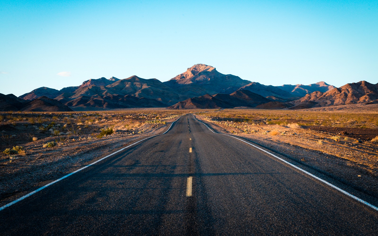 Eine lange straße in der mitte einer wüste mit bergen im hintergrund (usa, death valley, straße, berg, valley)