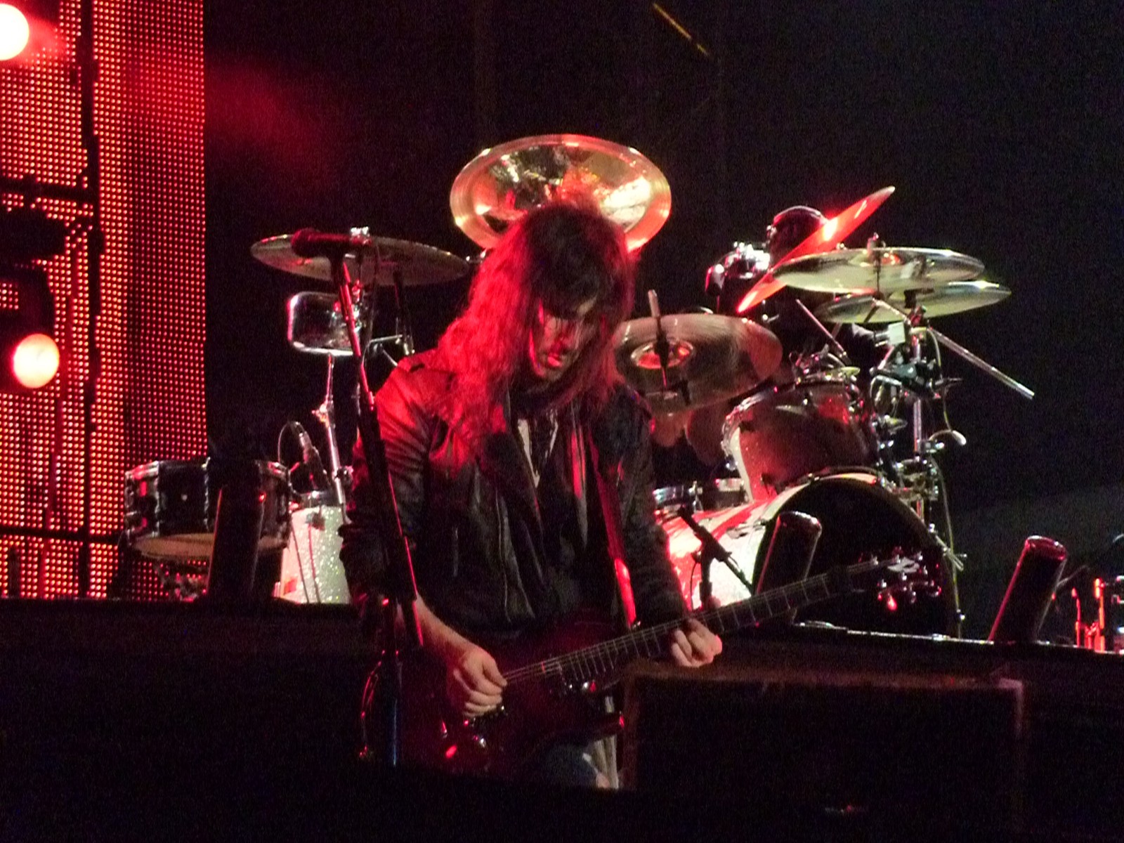 Homme aux cheveux longs jouant de la guitare sur scène (batteur, concert rock, grosse caisse, tambour, percussion)