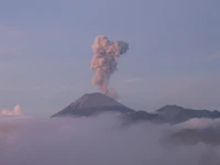 Majestuoso estratovolcán erupcionando entre nubes al amanecer