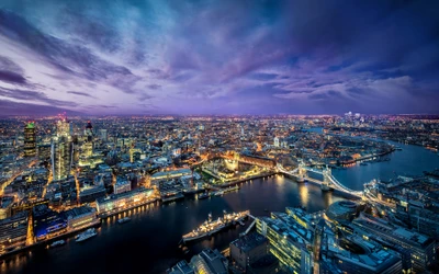 Uma deslumbrante vista aérea de Londres ao crepúsculo, mostrando o vibrante horizonte da cidade iluminado pelas luzes da cidade contra um fundo de céu roxo, com o rio Tâmisa serpenteando pela paisagem.