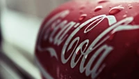 Close-up of a Coca-Cola can glistening with condensation, showcasing its iconic red color and logo.