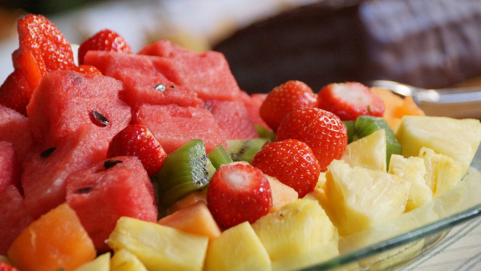 Un plato de frutas sobre una mesa (fruta, comida, fresa, copa de frutas, piña)