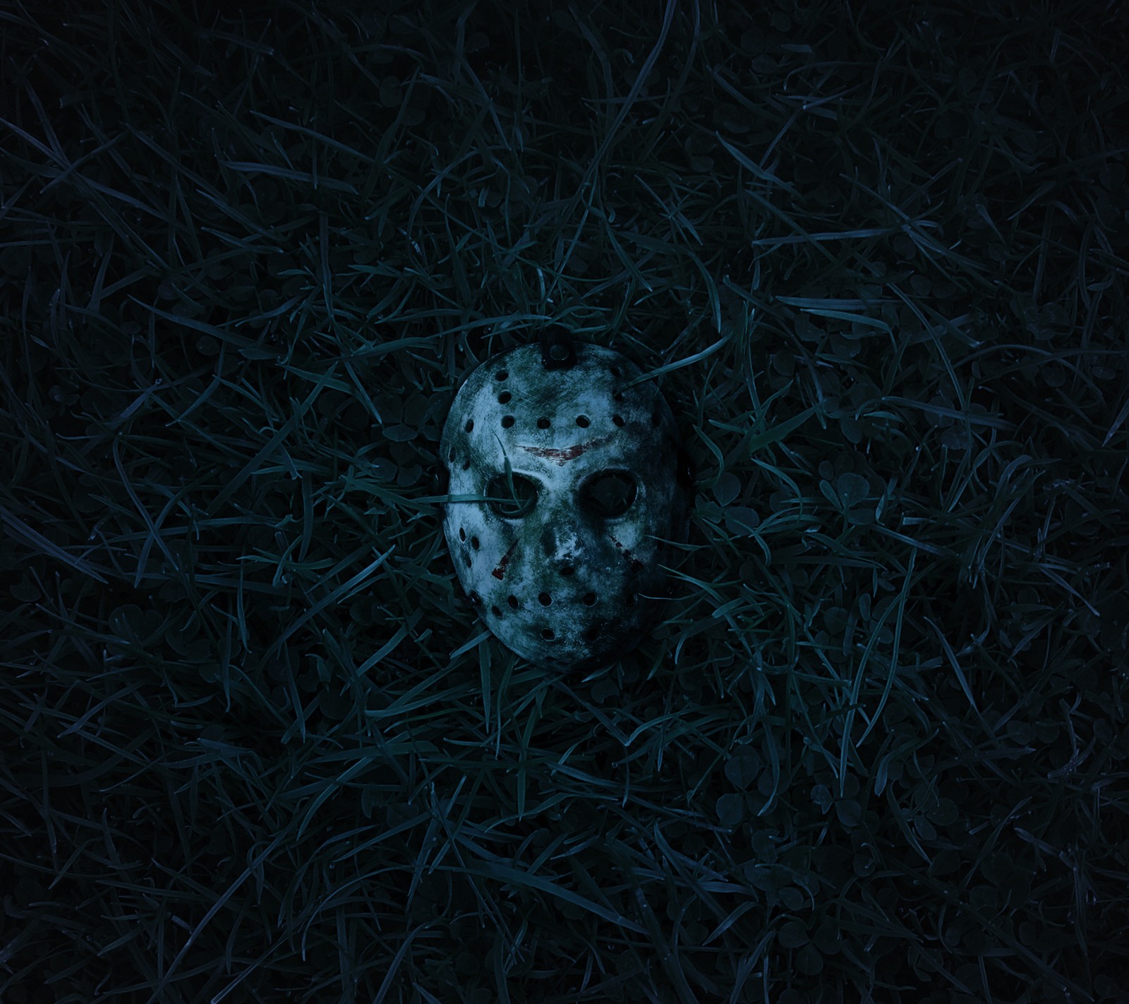 A close up of a scary mask laying in the grass (barbaivan, blue, grass, lake)