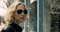 Jennifer Lawrence in Sonnenbrille, die coole Zuversicht vor dem Hintergrund einer verschneiten Straße ausstrahlt.