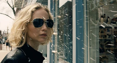 Jennifer Lawrence de óculos de sol, exalando confiança legal contra um fundo de uma rua nevada.