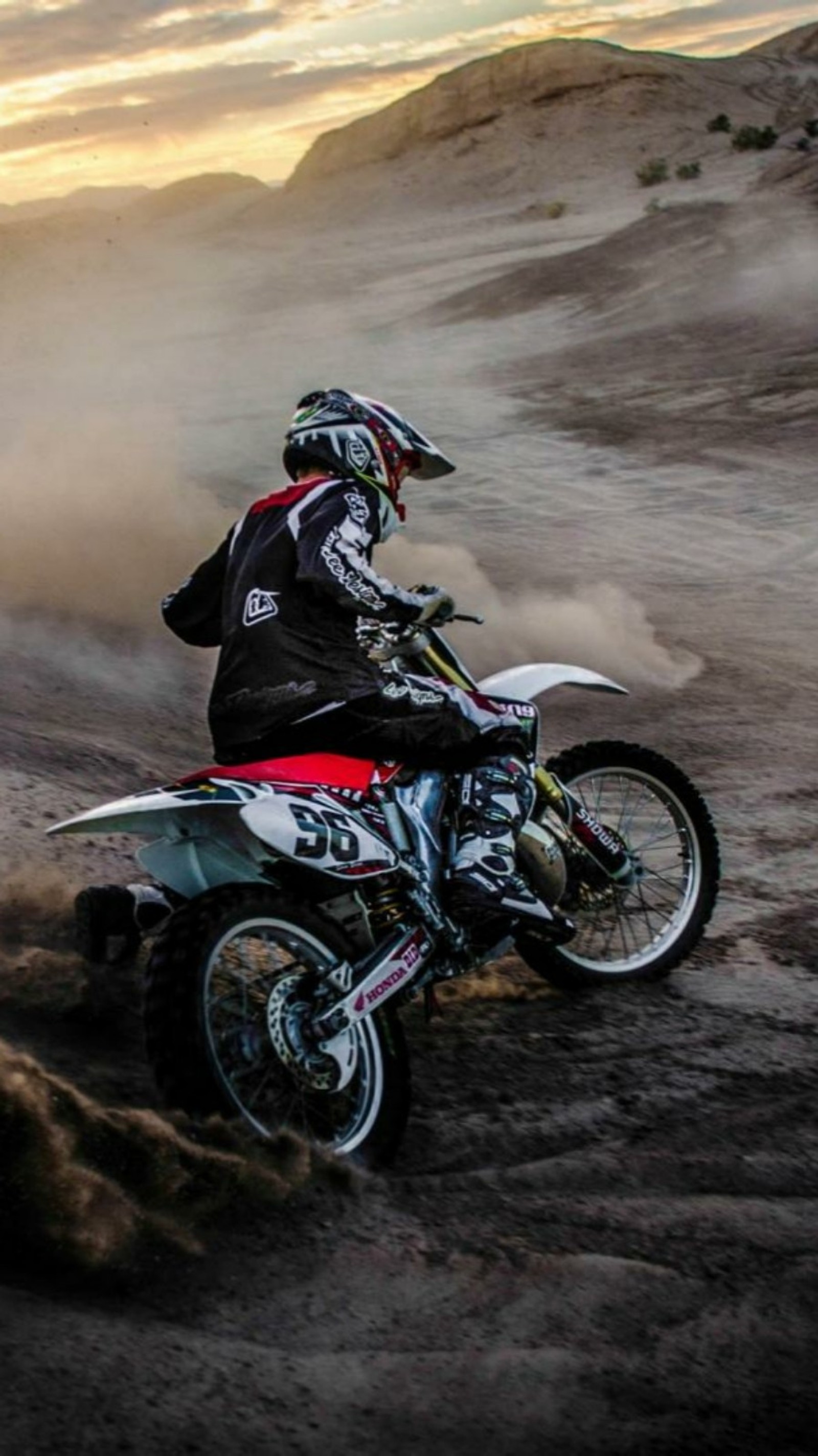 Motard dans le désert avec de la poussière s'élevant du sol (vélo, championnat, saleté, honda, motocross)