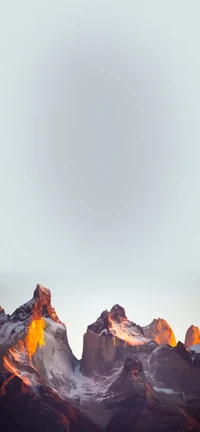 Dramatic peaks of Torres del Paine bathed in morning sunlight, showcasing the majestic beauty of a mountainous landscape.