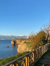 Malerische Klippenansicht mit Blick auf einen ruhigen See und schneebedeckte Berge