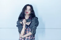 Jisoo do BLACKPINK em uma pose estilosa e ousada com maquiagem vibrante e um traje xadrez contra um fundo elegante.