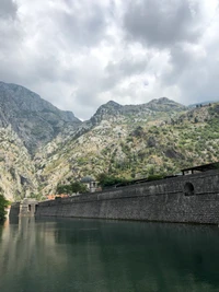 Fjord majestuoso flanqueado por montañas imponentes y aguas serenas bajo un cielo nublado.