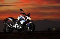 Motocicleta Honda silhuetada contra um céu dramático ao pôr do sol