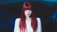 Minnie from (G)I-DLE with striking red hair, exuding a fierce presence in a white outfit against a dark, atmospheric backdrop.