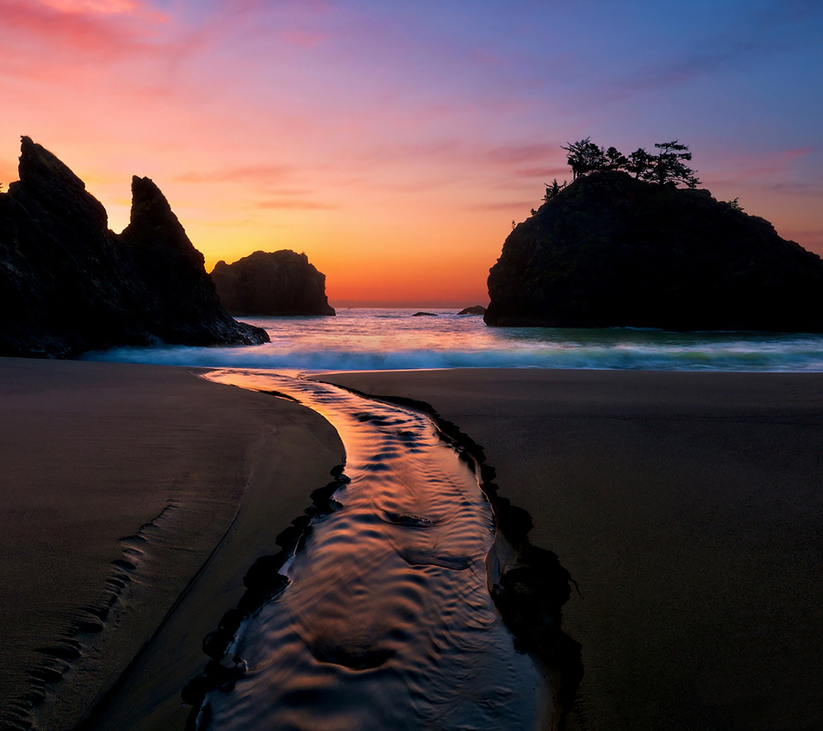 Uma vista árabe de uma praia com um riacho de água correndo entre duas pedras (hd, natureza)