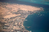 Vista aérea da costa de Hurghada, mostrando o estuário, o movimentado resort à beira-mar e a paisagem desértica contrastante encontrando o mar turquesa.