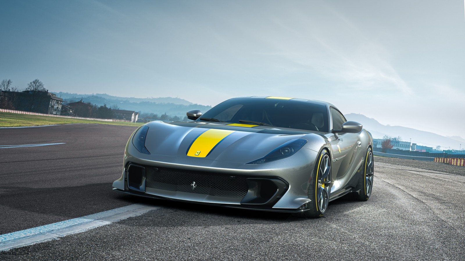 Um carro esportivo prateado dirigindo em uma pista com montanhas ao fundo (ferrari v12 versão especial, ferrari v12 versione speciale, 2021, 5k, carros)