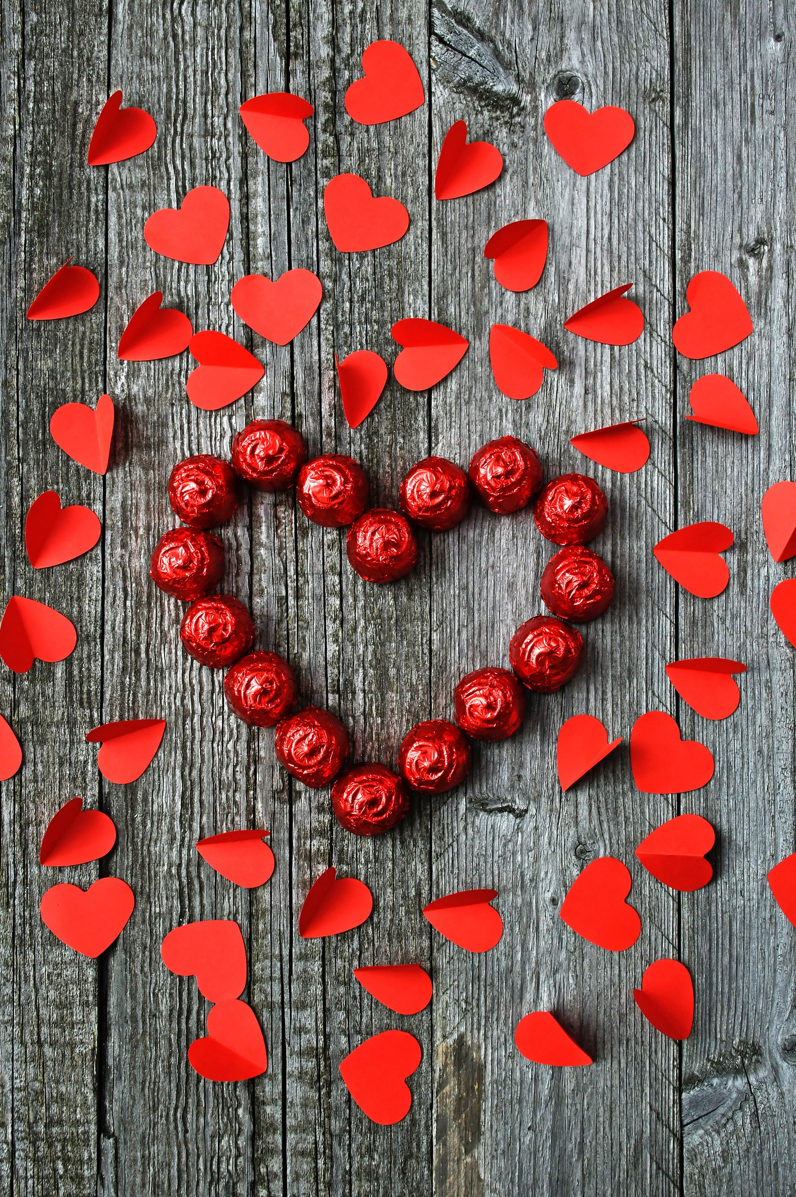 There is a heart made out of red paper hearts on a wooden table (heart, valentines day, red, love, plant)