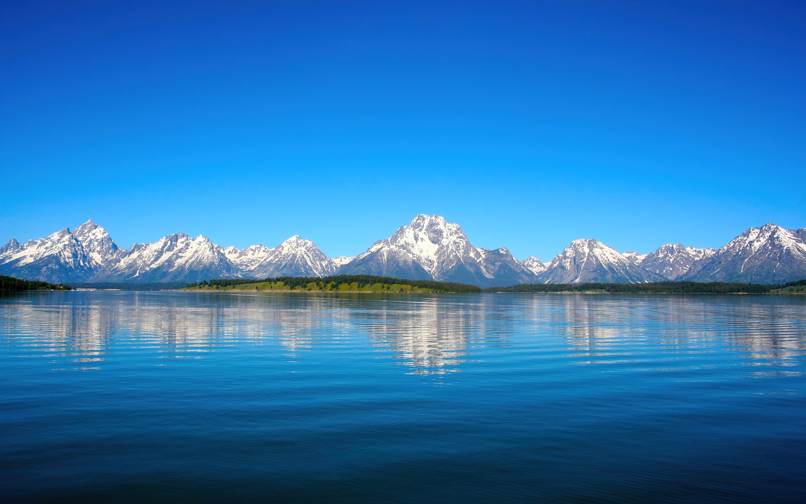 Una vista de las montañas y el agua desde un barco en un lago (jenny lake, paisaje, parque nacional grand teton, día soleado, reflejos)