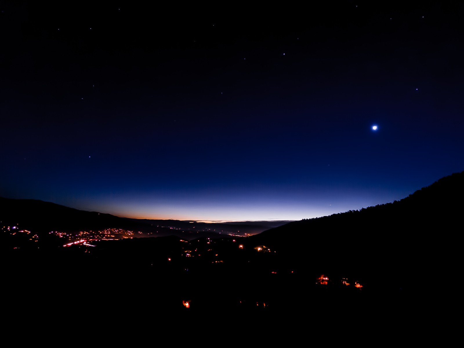 Vista nocturna de una ciudad con una brillante luna en el cielo (noche, oscuridad, naturaleza, azul, atmósfera)