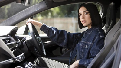 Dua Lipa in einem stylischen Auto, das ihr selbstbewusstes und modernes Wesen zeigt.