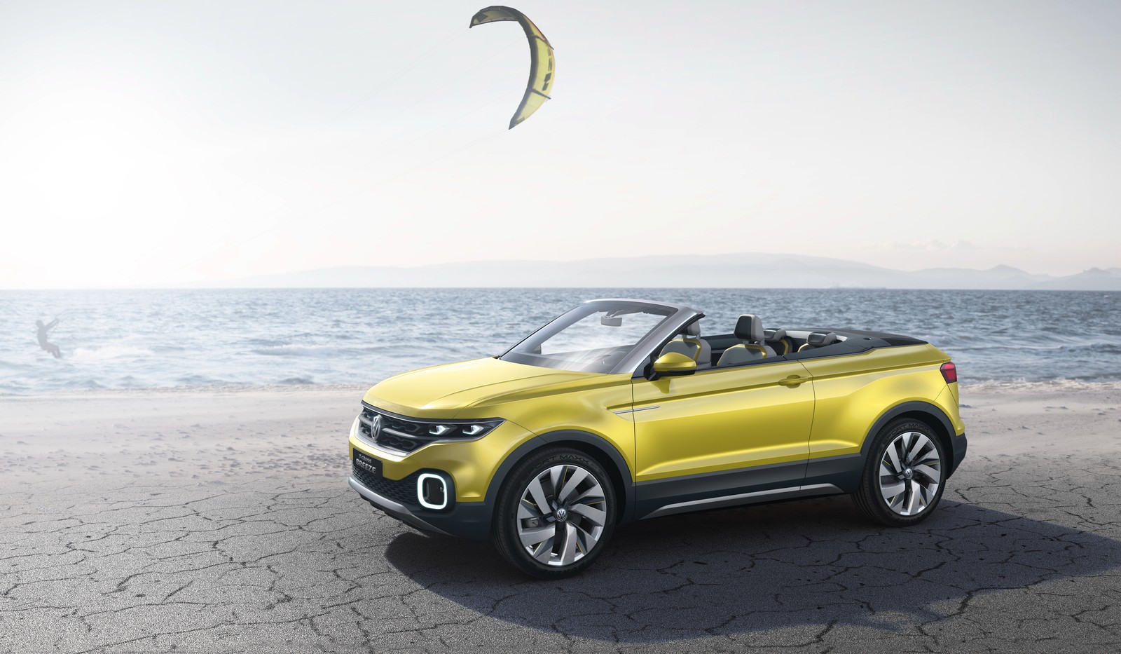 A yellow volkswagen suv parked on the beach with a kite in the sky (volkswagen, car, range rover, convertible, mid size car)