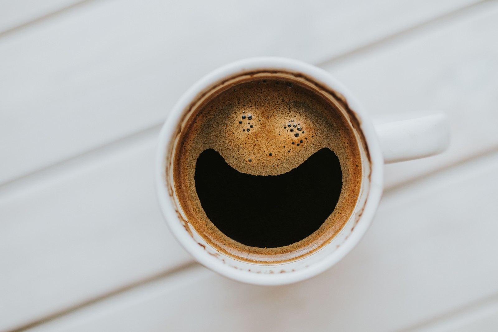 Un gros plan d'une tasse de café avec un visage souriant dessus (espresso, café, tasse à café, tasse, caféine)