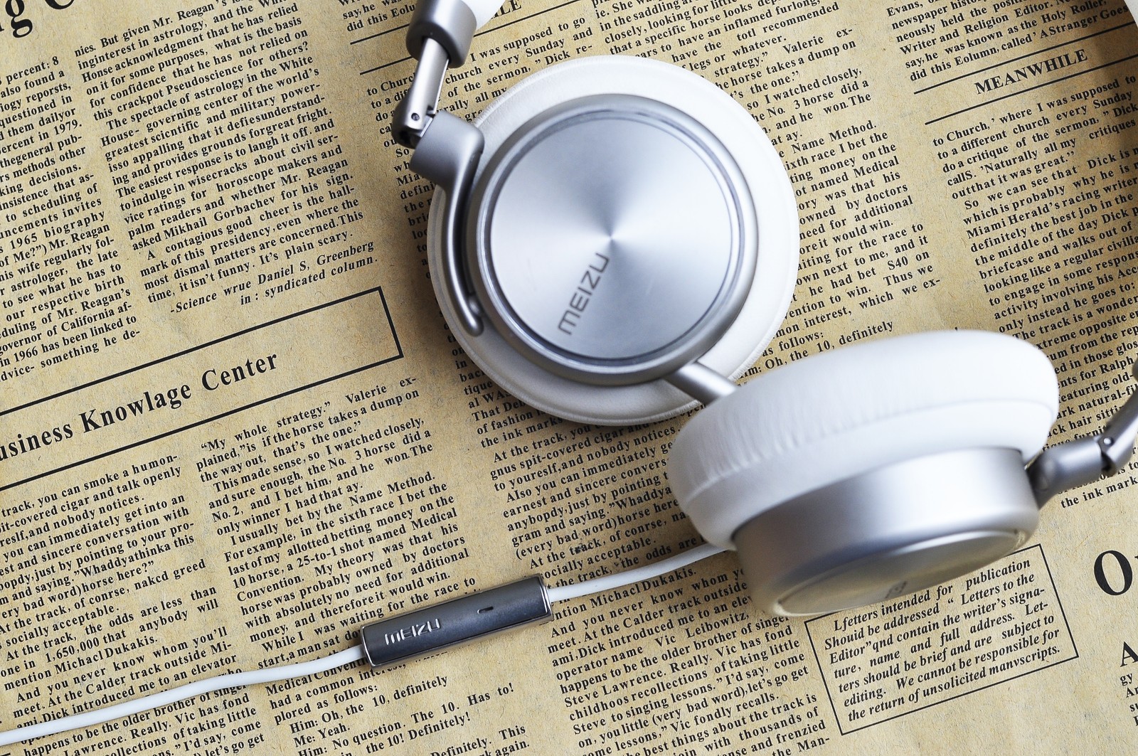 A close up of a pair of headphones on a newspaper (headphones, audio equipment, gadget, fashion accessory, headset)