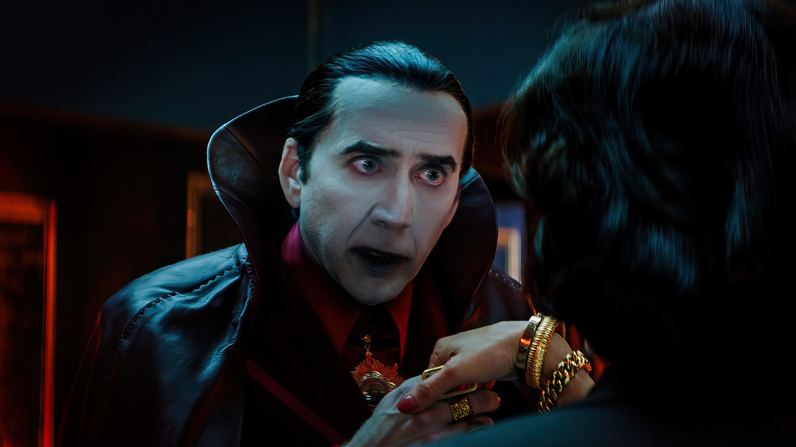 A close up of a person in a black jacket and a woman in a red dress (renfield 2023, movie, dracula, nicolas cage)