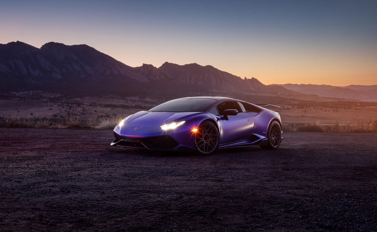 Un coche deportivo morado estacionado en un área desértica con montañas al fondo (lamborghini huracán, lamborghini huracan, paisaje, 5k, coches)