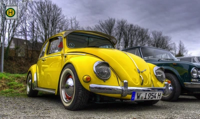 Fusca amarelo vintage com rodas clássicas, estacionado ao lado de outro carro sob um céu nublado.