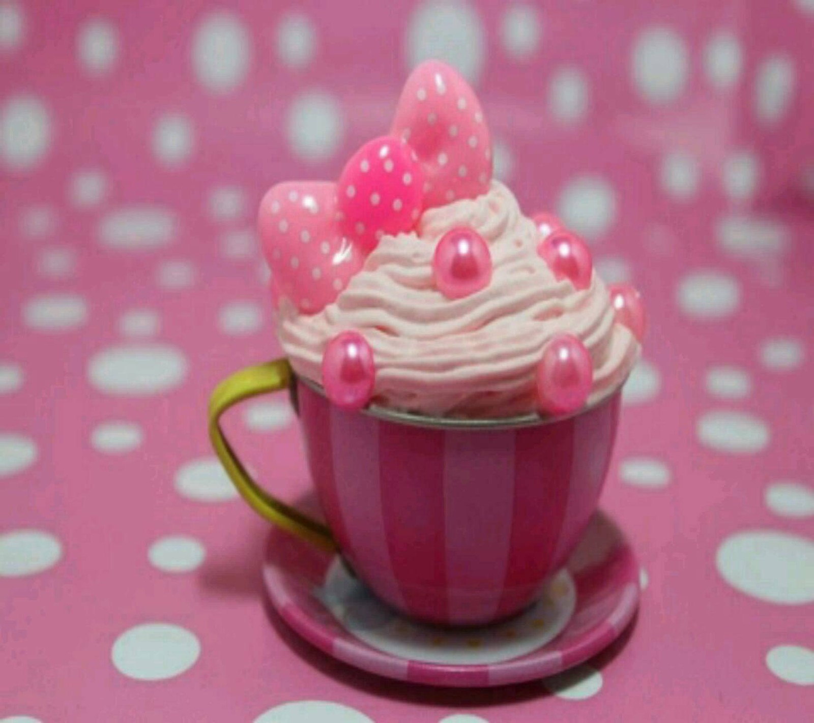 Hay un cupcake en una taza con decoraciones rosas sobre él (crema, mini cup)