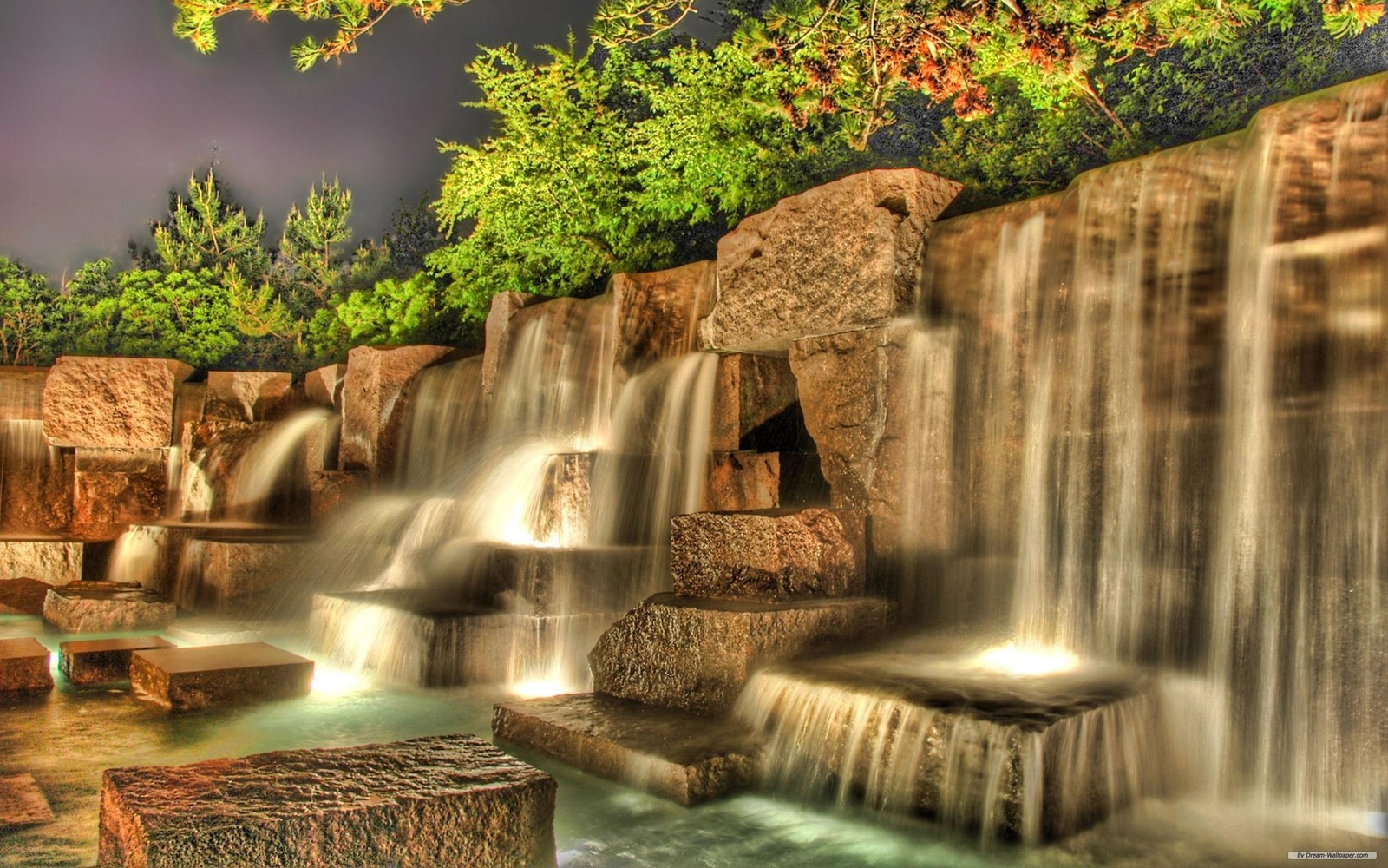 Uma cachoeira em um parque com um céu escuro e árvores ao fundo (cachoeira, natureza, água, curso dágua, elemento de água)