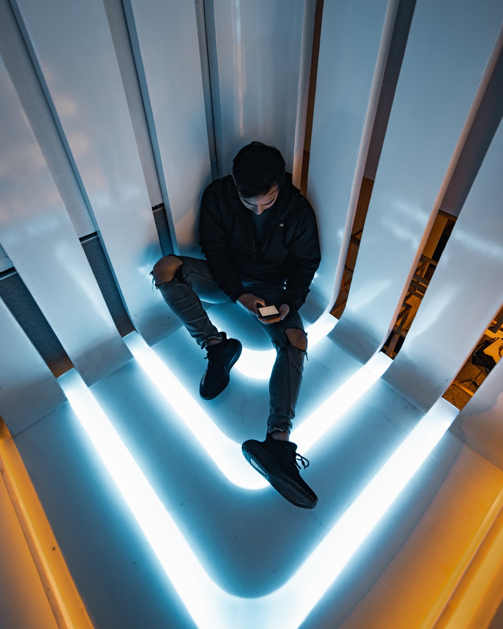 Giraffen mann sitzt auf einer treppe mit einem handy in der hand (licht, blau, tageslichtnutzung, linie, himmel)