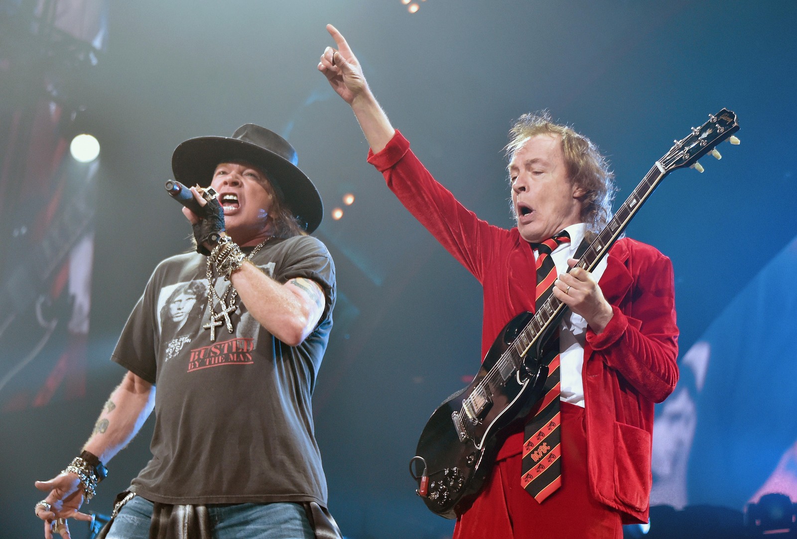 Dos hombres con sombreros cantando y tocando guitarras en el escenario (concierto, acdc, ac dc, guns n roses, desempeño)