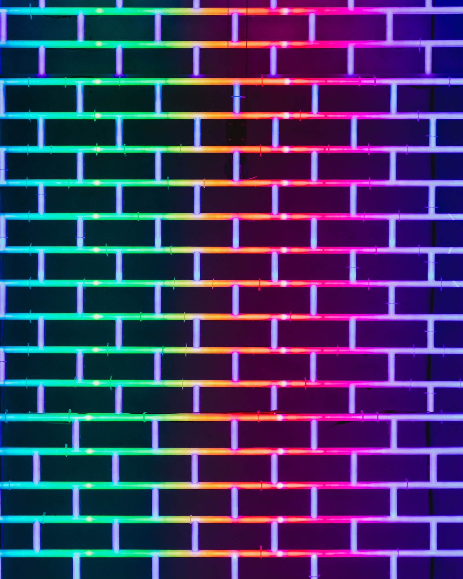 A close up of a colorful light that is shining on a wall (brick, line, purple, violet, pattern)